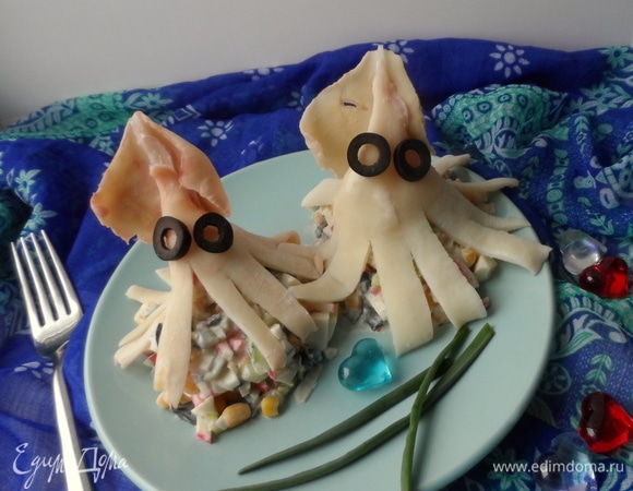 Разложить салат и украсить кальмаром, уложив его сверху. Сделать глазки из маслин. Вот такая веселая семейка кальмарчиков получилась.
