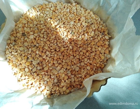 Поместить на тесто бумагу для выпечки и насыпать груз. Фасоль или горох подойдет. Выпекать 15 минут с грузом, потом убрать его. И еще 5 минут допечь.