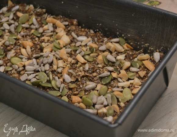 Выложить тесто в форму, сверху посыпать орехами, тыквенными семечками и кориандром. Выпекать 30–35 минут при 175°C.