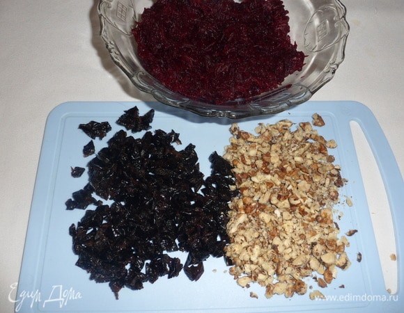 Вареную свеклу натереть на средней терке. Подготовленный чернослив мелко нарезать. Грецкие орехи измельчить.