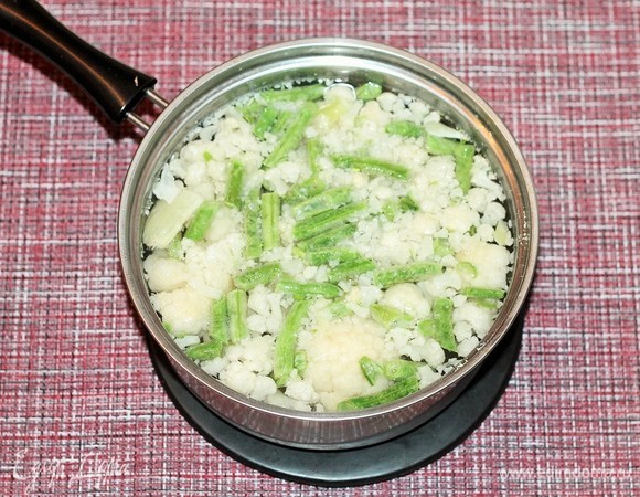 Цветную капусту разберите на соцветия и добавьте в кипящую воду. Сюда же добавьте стручковую фасоль, 1–2 минуты бланшируйте. Затем слейте воду через сито.