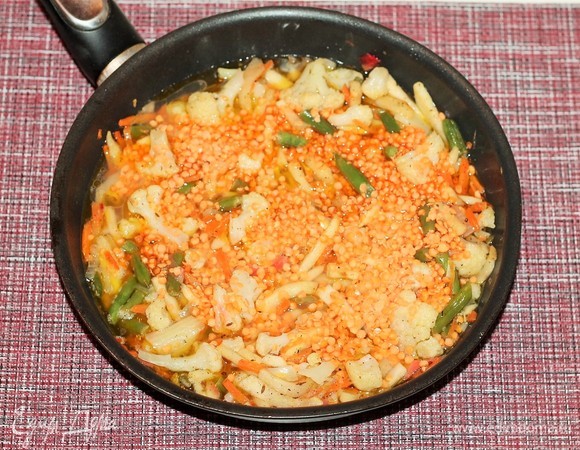 Влейте 250 мл овощного бульона, всыпьте чечевицу и перемешайте, накройте сковороду (или кастрюлю) крышкой и тушите до готовности на слабом огне.