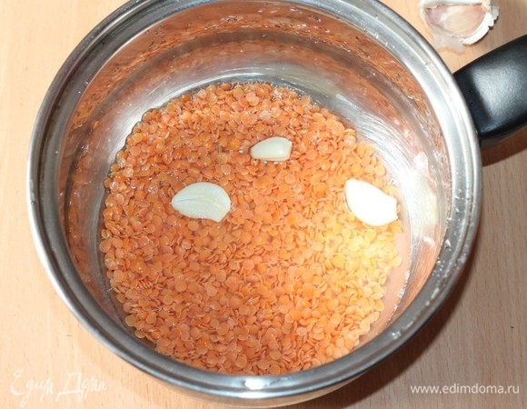 Чечевицу высыпать в кастрюлю с толстым дном, добавить чеснок и залить в три раза большим объемом холодной воды. Довести до кипения.