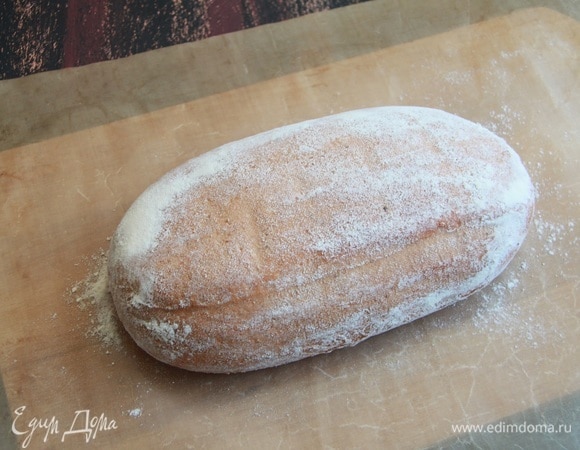 Духовку разогреть в течение 1 часа до 250°C. За 20 минут до посадки хлеба в печь, поставить емкость с водой для создания пара. Перевернуть заготовку на антипригарный коврик или пекарскую бумагу.