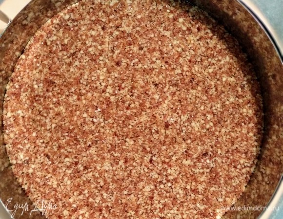 Готовим корж. Все ингредиенты смешать в кухонном комбайне или блендере с S-образным лезвием до получения липкой массы. Выложить полученную массу в форму. Равномерно распределить ложкой массу по форме, плотно прижимая ко дну. Отставьте готовый корж в сторону.