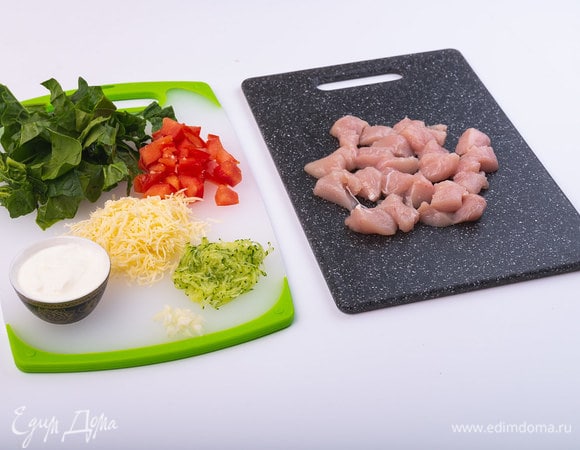 Филе курицы нарезать на кусочки размером 1,5–2 см. Сыр и огурец натереть на мелкой терке. Шпинат нарезать крупно, помидоры — кубиками по 1 см. Чеснок мелко порубить.