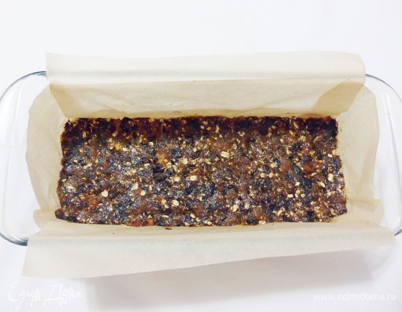 Выложить в форму полученную массу из сухофруктов, распределить ровным слоем по дну формы. Для облегчения выравнивания массы можно слегка смачивать пальцы водой.