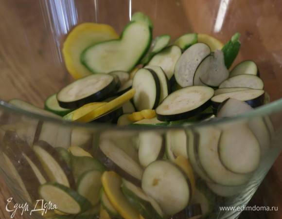 Баклажаны, цукини и патиссоны нарезать тонкими кружками и выложить тонким слоем в жаропрочную керамическую форму.