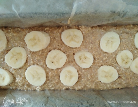 Духовку разогреть до 180°C. Прямоугольную форму выстелить пергаментом и смазать растительным маслом. Вылить тесто и разровнять. Оставшийся банан нарезать, сбрызнуть соком лимона, разложить сверху кекса.