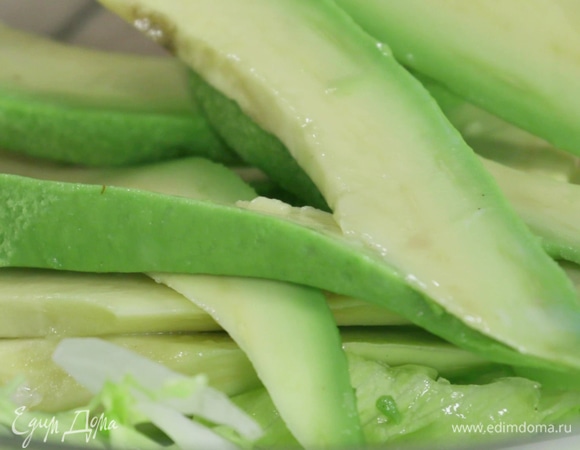 Половину авокадо сбрызнуть соком лимона от потемнения, очистить и нарезать тонкими слайсами.