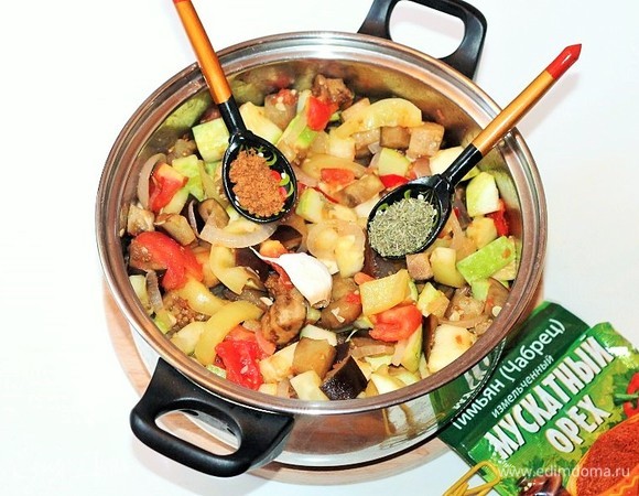 Закладываем в казан (или кастрюлю) остальные подготовленные овощи: баклажаны, кабачки и помидоры. Добавляем приправу: тимьян, мускатный орех, перец черный молотый и соль, перемешиваем и оставляем тушиться на 3 минуты.