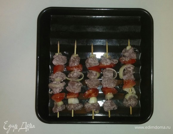 Спустя 4 часа достаем маринованное мясо из холодильника и начинаем собирать шашлык. Для приготовления шашлыка в духовке я использовала длинные шпажки. После того как все ингредиенты нанизаны на шампуры (шпажки), выкладываем их на противень. Для приготоаления шашлыка взять противень для запекания с прорезями и поставить его на обычный противень, чтобы мясо именно жарилось, но при этом его сок стекал в нижний противень. Разогреваем духовку до 200°C и ставим в нее противень с шашлыком на 40 минут (время приготовления зависит от духовки). Через 20 минут после начала запекания нужно перевернуть шашлык и продолжить его запекание. Если после нанизования ингредиентов на шпажки остались овощи, в том числе и лук из маринада, то можно их добавить к шашлыку за 10 минут до окончания приготовления.