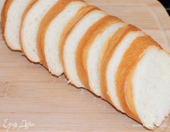 Багет нарежьте ломтиками (8 шт). Включите духовку на 180°C.
