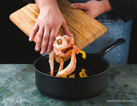 Сковороду разогрейте со сливочным маслом, выложите на сковороду креветки и перец, посолите и поперчите. Готовьте 3–4 минуты.