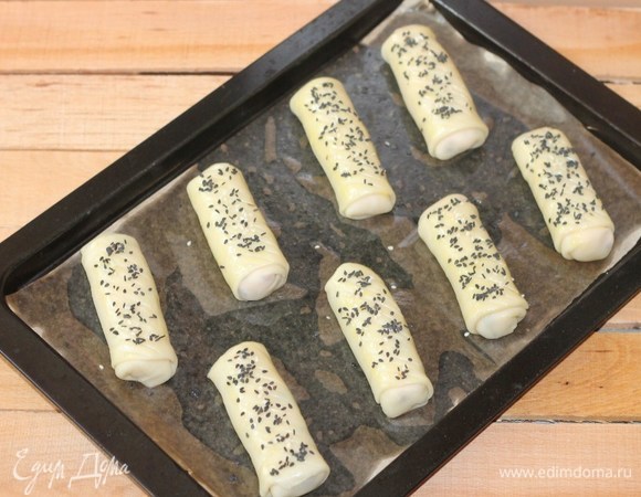 На противень кладем бумагу для выпечки, смазываем растительным маслом и раскладываем трубочки. Смазываем трубочки желтком, взбитым с молоком, и посыпаем кунжутом или тмином.