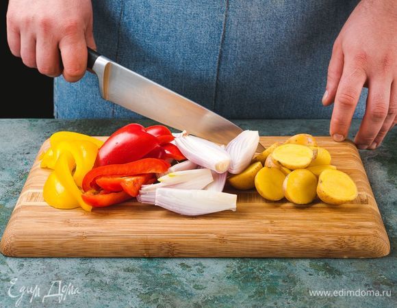 Тем временем картофель разрежьте пополам, лук, болгарский перец и рыбу нарежьте крупно.