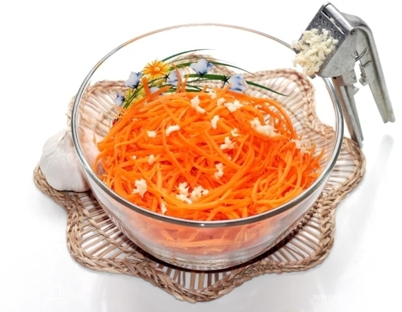 Зубчики чеснока очистить и спрессованными добавить к моркови. Растительное масло нагреть в небольшой емкости и в раскаленном виде вылить сверху на чеснок, перемешать. И в конце готовки добавляем лимонный сок.