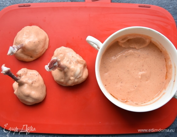 Для маринада смешать в миске растительное масло, соль, томатную пасту, сметану, майонез, сухой чеснок, паприку и острый молотый перец. Каждую часть крыла обмазать маринадом с помощью кулинарной кисточки либо окунуть в смесь.