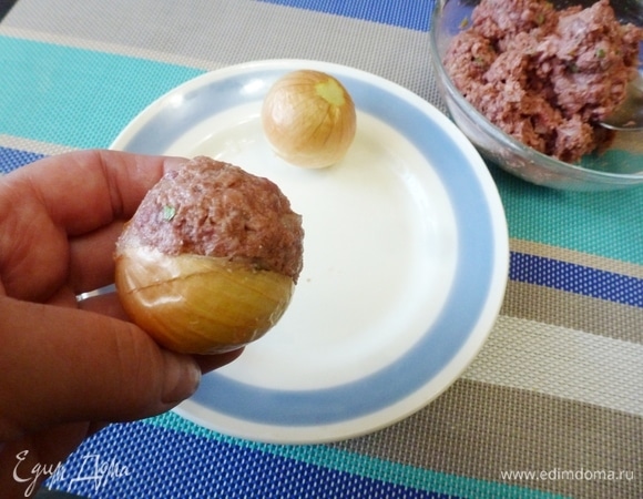 От фарша отделить небольшие шарики и поместить в вырезанное место в луке. Таким образом приготовить все луковицы. Выложить в форму, полить оливковым маслом и отправить в духовку запекаться на 30–40 минут при температуре 190–200°C.