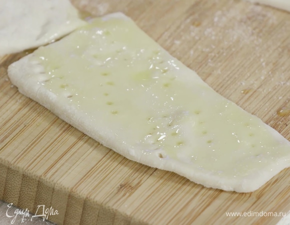 Смешать растопленное сливочное масло с сахарной пудрой и смазать им тесто.