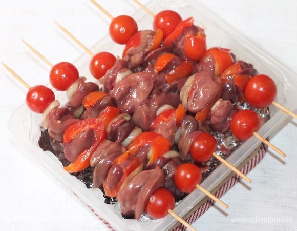 Достаем маринованную куриную печень из холодильника и аккуратно нанизываем на шампуры или деревянные шпажки. Если вы решили использовать деревянные шпажки, то их нужно предварительно замочить минут на 20 в воде, чтобы во время запекания они не горели. В начале нанизываем помидорчик черри, затем — один конец полоски перца, потом — печень, второй конец перчика и помидор. Шашлык получается не только вкусным, но и аккуратным за счет того, что печень немного завернута в полоску перца.
