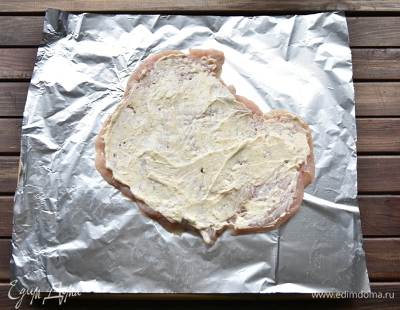 Творожный сыр смешать с солью, чесноком и приправой для курицы. Отбитое филе переложить на кусок фольги. Смазать смесью творожного сыра со специями.