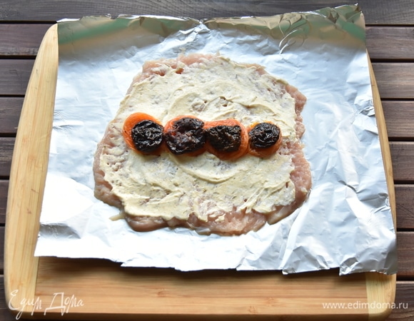 Сверху на сыр по всей длине филе уложить дольки кураги и чернослива.