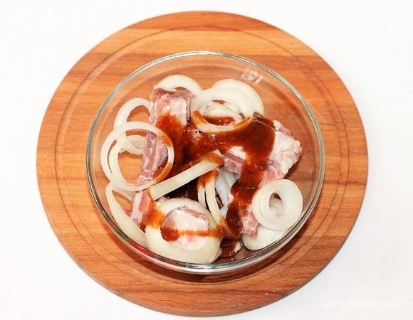 Промойте и обсушите ребрышки бумажным полотенцем. Нарежьте ребрышки на порционные кусочки. Добавьте очищенный и нарезанный кольцами репчатый лук, маринад для шашлыка (кетчуп шашлычный), перемешайте. Уберите ребрышки в холодильник на 3 часа, а лучше на ночь.