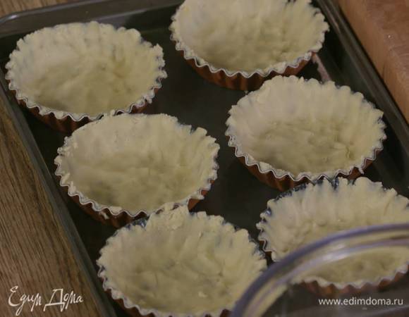 Формочки для тарталеток смазать оставшимся сливочным маслом, выложить в них тесто тонким слоем, так чтобы получились бортики, и отправить в морозильник на 5‒10 минут или в холодильник на 15 минут.