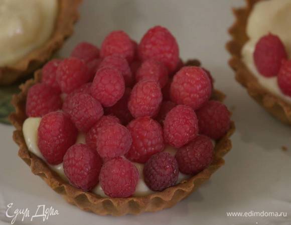 Наполнить тарталетки охлажденным кремом и украсить ягодами малины.