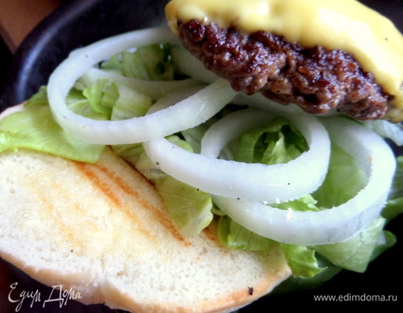 Собираем бургер: на теплую булочку положить салат, лук, котлету первую.