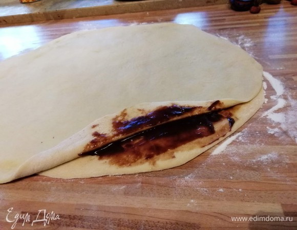 Дно разъемной формы диаметром 26 см застелите бумагой для выпечки и слегка смажьте маслом бортик. Разделите тесто на 2 части и раскатайте на слегка посыпанной мукой поверхности 2 пласта прямоугольной формы. Первый смажьте 1/3 частью соуса и накройте вторым пластом.