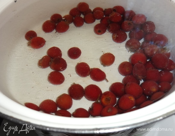 В кастрюлю налить воды, положить ягоды боярышника. У меня замороженные. Если свежие, то их надо вымыть, обрезать плодоножки. Довести до кипения, убавить огонь до среднего и варить боярышник 15–20 минут.