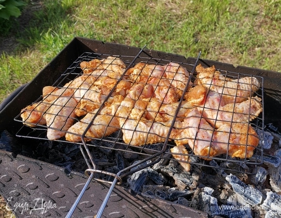 Распределяем куриные крылья на решетке, ставим на угли.