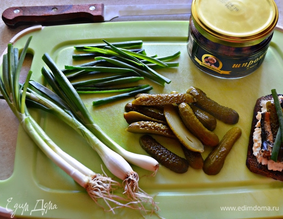 Для бутербродов понадобятся маленькие маринованные огурчики корнишоны. Разрежьте их вдоль пополам и выложите вместе с двумя рыбками поверх яичной начинки. Украсьте перьями зеленого лука. При желании огурчики можно нарезать кружочками, а также использовать соленые огурцы.