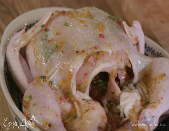 На дно жаропрочной керамической формы вылить оставшееся оливковое масло, выложить лук, на него поместить куриную тушку и смазать ее со всех сторон лимонной массой.