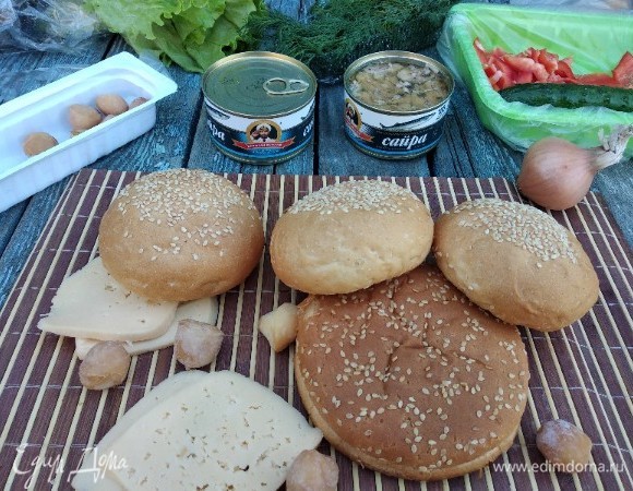 Подготовим ингредиенты: булочки разрезать на 2 части, сыр — на пластины, моем перец, укроп, листья салата. Нижние булочки я полила немного соусом из-под рыбы. Первый слой на булочку выложить сыр.