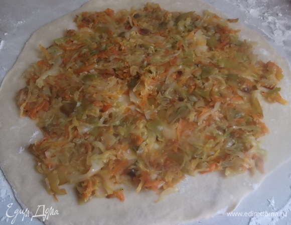 Тесто раскатать в пласт. Выложить тушеную капусту тонким слоем. Свернуть в рулет. Нарезать на несколько сегментов.