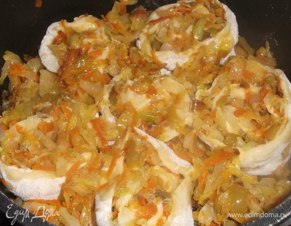 Оставшуюся начинку разделить пополам. Из одной половины сделать овощную подушку, на нее уложить нарезанные рулетики, укрыть оставшейся частью капусты. Влить оставшийся рассол.