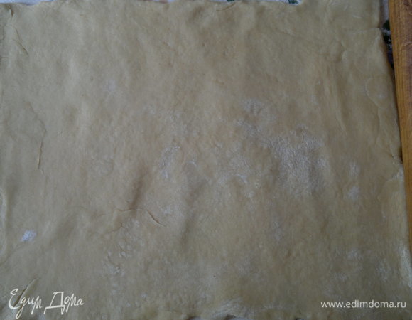 По истечении времени достать из холодильника больший кусок теста. Раскатать его в прямоугольный пласт на подпыленном мукой столе.