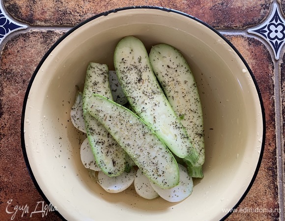 Разрезать лук и кабачок пополам. Посолить, добавить итальянские травы, ложку оливкового масла.