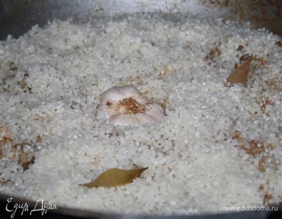 Кладем сверху промытую головку чеснока и пару лавровых листьев. Солим рис немного. Накрываем крышкой (крышку можно обмотать изнутри чистой х/б тканью, чтобы впитывала конденсат, но я этого не делала). Готовим час. Угли стабильные, но огня быть не должно, теперь наш плов как бы томится. Через полчаса снимите крышку, перемешайте рис по верху, не доставая шумовкой до зирвака. Затем деревянной палкой в нескольких местах проткните плов до самого дна, чтобы жидкость лучше выпаривалась. Накройте крышкой и готовьте еще полчаса.