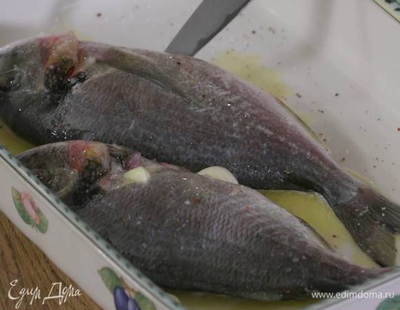 Рыбу выложить в жаропрочную керамическую форму, слегка посолить, поперчить, полить растопленным маслом, а зубчики чеснока поместить в брюшко.