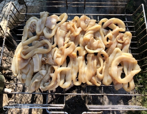 Выкладываем кольца кальмара на решетку и готовим на углях в течение 10 минут. Решетку переворачиваем.