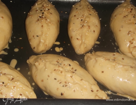 На смазанный растительным маслом противень выложить пирожки. Смазать смесью желтка с молоком. По желанию посыпать сверху кунжутом. Поставить в разогретую духовку. Выпекать при 200°C в течение 20 минут.