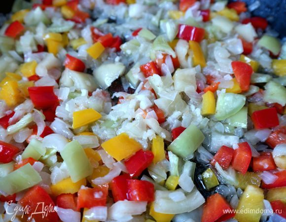 Затем добавить болгарский перец, освобожденный от семян и нарезанный на кубики со стороной 1 см, тушить до мягкости, добавив еще 3 ст. л. оливкового масла. Через минут 5 после обжаривания закрыть сковороду крышкой, продолжать тушить еще некоторое время.
