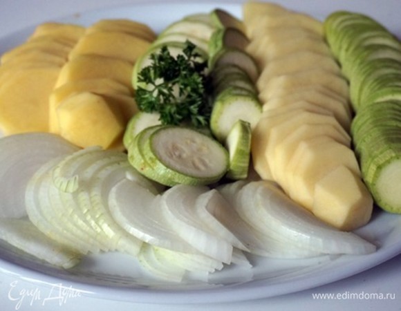 Нарезать картофель и цукини кружочками. Лук нарезать кольцами либо полукольцами. Зелень петрушки и чеснок мелко нарезать.