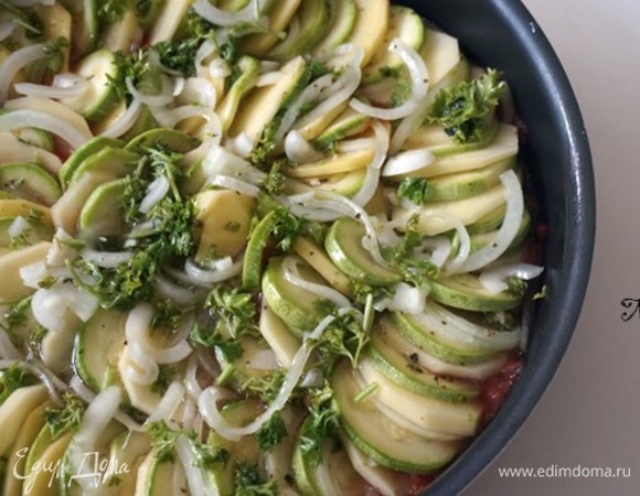 Разложить картофель, цукини и нарезанный лук на сковороде в круговые ряды, чередуя овощи.