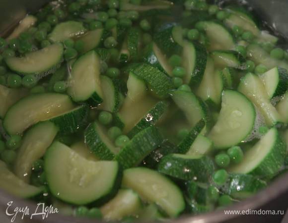 Всыпать в кастрюлю с цукини зеленый горошек, посолить, если понадобится, добавить немного бульона, все перемешать и еще немного поварить.