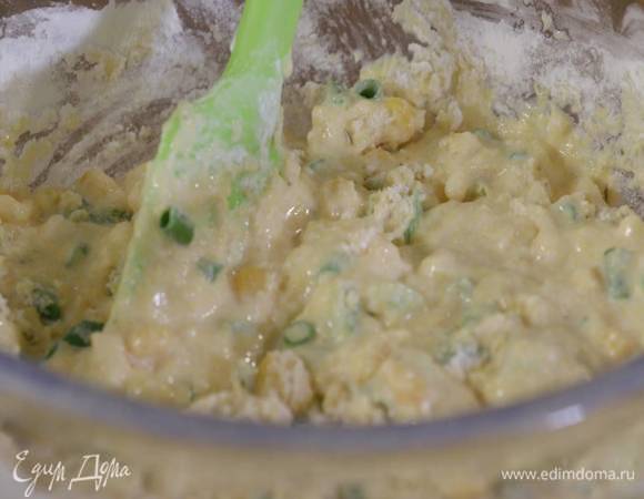 В отдельной посуде соединить поленту со сметаной, сахаром и яйцами, влить 120 мл оливкового масла и перемешать все в однородную массу, затем всыпать кукурузу, порезанный лук и перемешать.